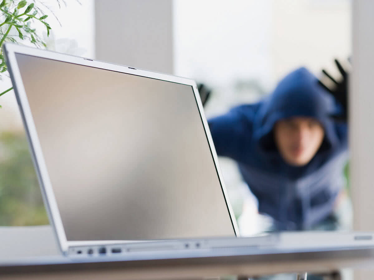 Laptop mit Einbrecher im Hintergrund
